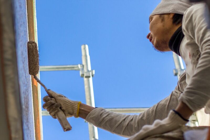 外壁にペンキを塗る職人